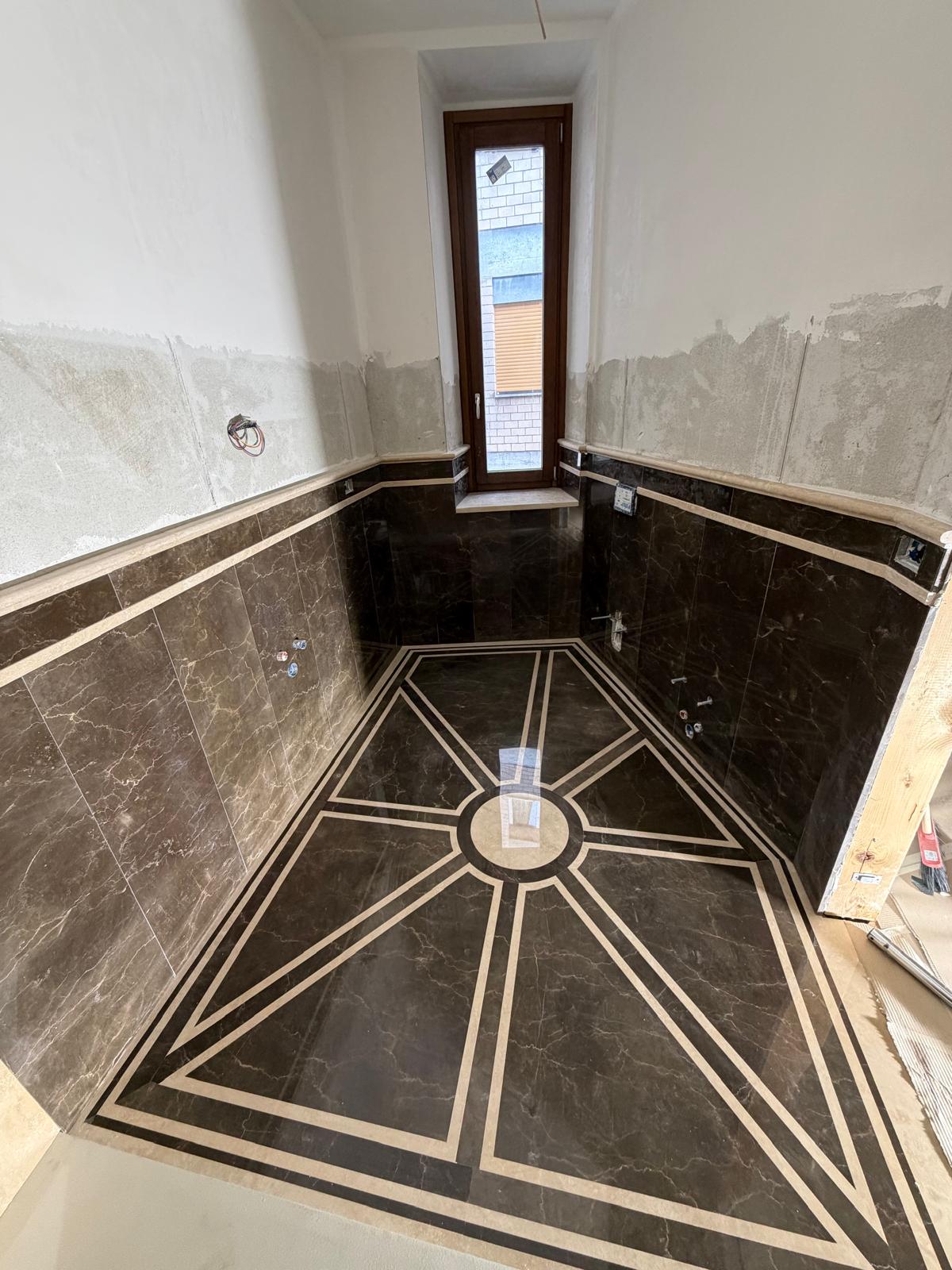 Bathroom clad in Emperador Brown marble with inlays